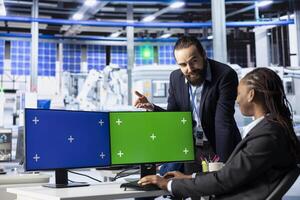 Happy photovoltaics factory manager using isolated screen PC to show worker how to optimize production flow. Upbeat solar panels plant supervisor monitors manufacturing process on chroma key computer photo