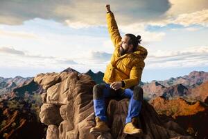 Satisfied adventure seeker stands at the top a towering mountain, taking in the epic view and feeling proud of his hiking achievement. Strong joyful trekker feels the rewarding experience. photo