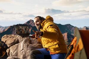 Adventure seeker having internet everywhere and using call discussion, chatting with colleagues on the top of the mountain. Hiker with a technology obsession and dependency. photo