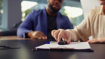 Customer in car showroom writing signature on paper after completing credit application and financing paperwork. Client in dealership signing financial paperwork, camera B close up photo