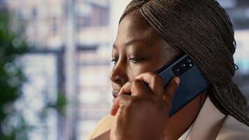 Woman director talking about growth plan on her mobile phone, conducting a client call working on project management tasks. Entrepreneur does negotiations via phone call for productivity. Camera A. photo