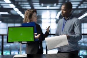 Focus on mockup tablet in front of data center inspector reviewing paperwork files next to manager. Close up of isolated screen device next to supervisor checking server farm documentation photo