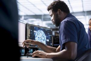 African american man in server farm uses artificial intelligence technology for increased productivity in startup. Machine learning specialist in data center workspace implementing AI driven solutions photo