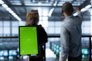 Close up of mockup tablet and data center admins developing disaster recovery plans. Focus on isolated screen device in front of server farm employees in blurry background testing failover scenarios photo