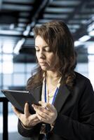 Data center technician using tablet, conducting security audits, preventing vulnerabilities. Employee using device to review firewall rules, enforcing cybersecurity protocols, logging incident details photo