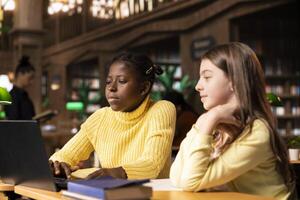 Diverse pupils at a public library attending a conference webinar lesson, enjoying an online class lecture as part of an online education program. Elementary school courses via web call. photo