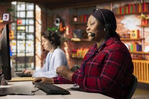 Happy call center worker analyzes customer feedback data, working to reduce complaints. Friendly customer service employee at computer desk using problem solving skills to address customer needs photo