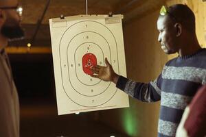Shooting gallery worker teaching students how to hit bullseye with handguns. Firing range expert providing guide to achieve high level of proficiency with firearms while shooting targets photo