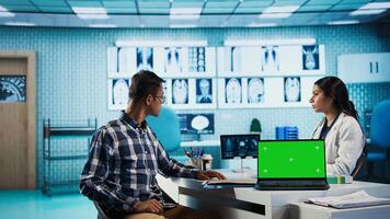 Indian medic consulting her patient in medical facility next to copy space, using advanced technology for scan interpretation and diagnostics. Expert gives advice based on records. Camera B. photo