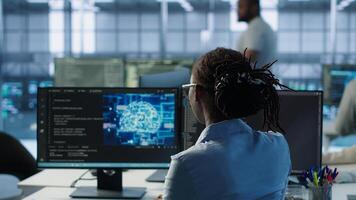 Engineer typing on computer in server hub, monitoring data center energy consumption using AI software. Technician inspecting rackmounts in server room using artificial intelligence tech, camera A photo