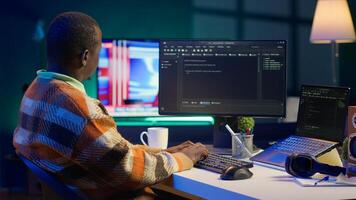 Programmer in home office concentrating on finding bugs while he codes on his computer. African american IT admin frowning while looking at screen, confused by errors in lines of code. Camera A. photo