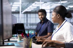 African american admin in data center workspace running system diagnostic tests and error checking utilities to fix problems. Woman in server hub looking for network issues affecting rigs performance photo