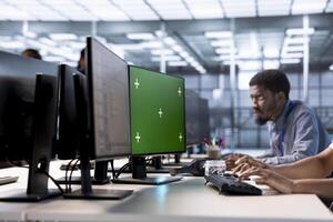 Engineer in server hub ensuring data remains shielded from potential threats using green screen PC. Employee safeguarding data center hardware against malicious access with mockup computer display photo