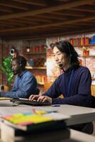 Experienced call center senior agent talking in headset mic, helping customers regain access to accounts and devices. Asian man in customer center assisting clients needing help resetting password photo