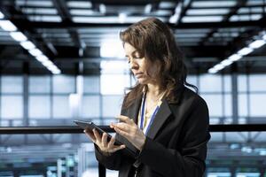 Technician in data center uses tablet, developing disaster recovery plans, managing continuity strategies. Woman in server hub tests failover scenarios, ensuring data accessibility during disruptions photo