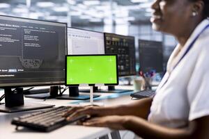 Programmer using green screen tablet to check for signs of failure in data center supercomputers. Woman working on mockup device to prevent damages in server farm, monitoring systems photo