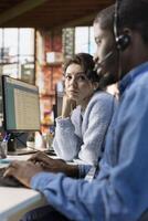 Call center agents collaborating, logging customer interactions in spreadsheet document on computer. Customer service agent and african american coworker using customer service management software photo