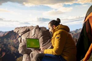 Mountaineer stands at the peak with satisfaction and uses mockup screen, hiker admires breathtaking view with crisp air on mountain top. Scenic surroundings highlights determination. photo