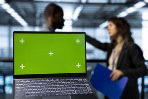 Mockup laptop used by data center admins in blurry background reviewing equipment diagnostics. Close up of chroma key notebook used by workers adjusting server room configurations photo