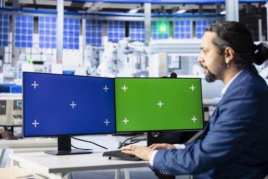 Engineer in photovoltaics factory reviewing system logs on isolated screen computer displays to identify errors. Photovoltaic plant worker adjusting manufacturing parameters on mockup PC monitors photo