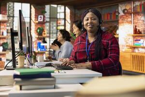 Portrait of smiling call center agent in office helping customers by answering questions, solving their issue. Happy woman in customer support workspace using headset mic to talk with clients photo