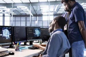 Admin doing brainstorming with colleagues in server farm, using artificial intelligence technology for increased productivity. Team of data center coworkers implementing AI driven solutions photo