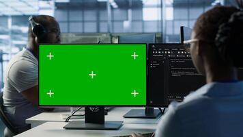IT specialist in server farm using green screen PC ensuring valuable data remains shielded from threats. Woman safeguarding hardware against unauthorized access using mockup computer, camera A photo