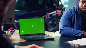 Salesman using isolated screen laptop to present car addons options to clients, trying sway them to make purchase. Showroom agent offers warranty to customers, holding chroma key notebook, camera A photo