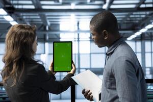 Data center admins using isolated screen tablet to calibrate energy usage. Server hub workers using chroma key device to inspect UPS configurations, doing maintenance on equipment photo
