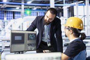 Photovoltaics factory coworkers doing brainstorming, finetuning system settings for maximum efficiency. Engineers talking, working together on solar panels plant assembly lines configuration photo
