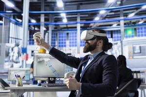Photovoltaics factory engineer using VR gear to conduct robotic machinery testing. Solar panels plant expert using virtual reality technology to consult manufacturing parameters, making adjustments photo