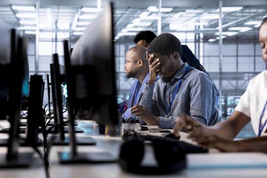 Tired engineer feeling headache while reconfiguring server farm to optimize it for data processing requirements. Stressed man working overtime to ensure data center gear operates efficiently photo