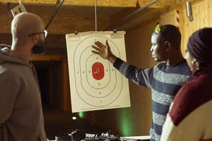 Group of friends having fun in shooting gallery, comparing results after hitting targets. Coworkers in teambuilding entertained by shooting bullseyes at firing range, doing competition photo