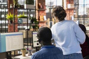 Customer service manager supervising agents logging customer interactions in CSM system. Call center supervisor overseeing workers using customer service management software photo