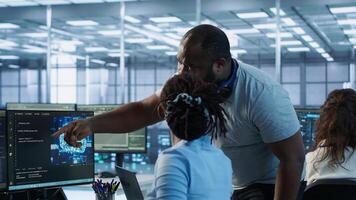 Manager coming to technician desk to give instructions on doing maintenance on artificial intelligence neural networks. Supervisor overseeing worker using AI system software, camera A photo