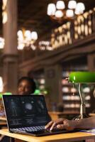 Med school student takes personal notes from anatomy research papers, studying healthcare methods for a medical career. African american pupil using books from the campus databases. photo