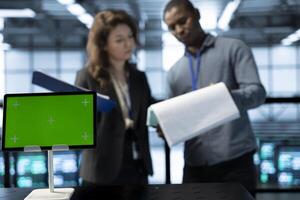 Isolated screen tablet in front of inspector next to server room engineer checking documents to ensure compliance with industry standards. Supervisor and employee inspecting data center files photo
