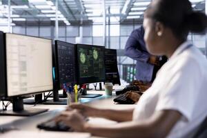 Computer scientist reconfiguring server farm to optimize it for data processing requirements of customers. African american woman working to ensure data center equipment operates efficiently photo