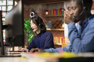 Call center senior operator using remote access tools to connect to customer devices remotely for troubleshooting. Experienced Asian customer center worker assisting users with installing software photo