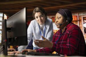 Call center supervisor providing support and guidance to intern, addressing questions. Customer support office onboarding specialist conducting orientation sessions for new agent using PC photo