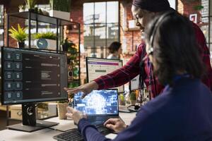 Call center onboarding specialist training new agent on helpful artificial intelligence tools. African american manager in customer support department office shows man how to use company AI software photo