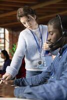 Call center manager providing guidance to african american intern, addressing questions. Customer service workplace onboarding specialist conducting orientation sessions for new agent, close up photo