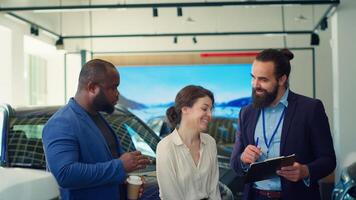 Car dealership salesman completing purchase paperwork and documentation after agreeing terms with customers. Agent giving sale contract for clients to sign after offering vehicle keys, camera A photo