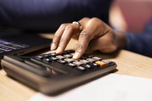 People using calculator to manage business taxes and accounting, tracking expenses for effective money management while they work remotely. Doing calculations for tax season. Close up. photo
