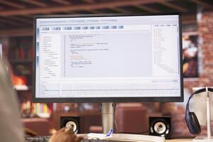 Coder at workstation programming on computer, writing lines of code, using development tools. Woman in home office trying to to finish debugging software before deadline, close up on PC monitor photo