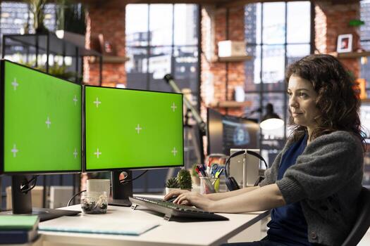 Employee in a smart office working on PC with isolated copy space on dual monitors, creative agency modern setup. Woman focused on graphic design, coding or AI powered tasks in optimized space. photo