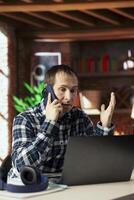 Unhappy manager in telephone call with employee offering negative feedback on project progress. Disappointed supervisor in home office berating teleworker at home during phone call photo