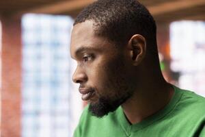 Close up of uncaring man showing indifference and apathy while staying at home, feeling depressed. Careless person with nonchalant indifferent expression on face in apartment photo