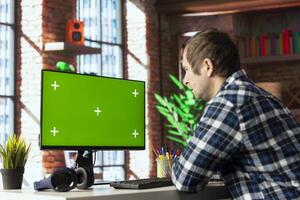 Teleworker in home office editing documents on mockup computer, updating reports and files, typing text. Freelancer managing digital paperwork within file directories on green screen PC photo