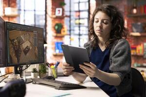 Young designer works on remodeling project using architectural software on PC to configure room layouts. The program allows her to drag and drop elements or assets, adjusting virtual furniture. photo